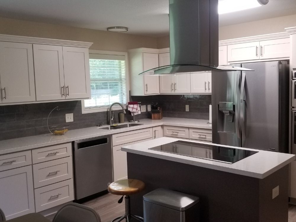 Modern kitchen design featuring white cabinetry, stainless steel appliances, and a central island with an induction cooktop, showcasing Trinity Construction's high-quality craftsmanship and luxury home renovations.