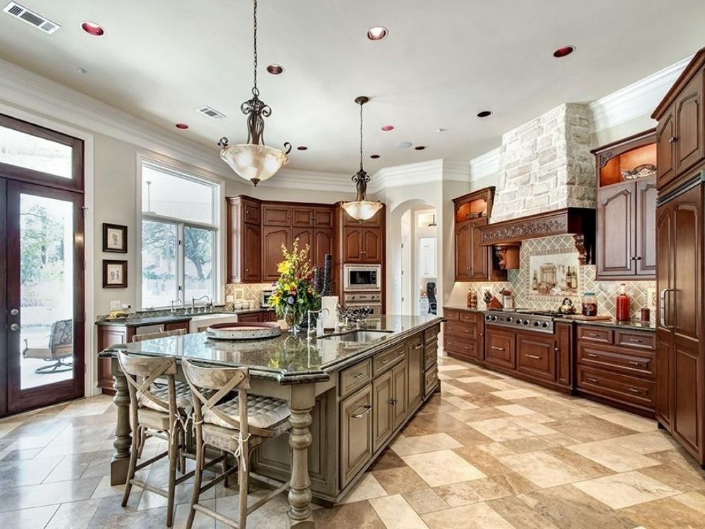 Custom luxury kitchen with dark wood cabinetry, granite countertops, and modern appliances, featuring a central island and elegant lighting, showcasing Trinity Construction's craftsmanship in home renovations.